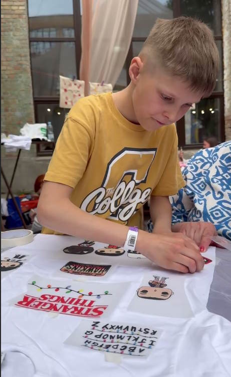 Хлопчик робить індивідуальну футболку з Дивними дивами на майстер-класі
